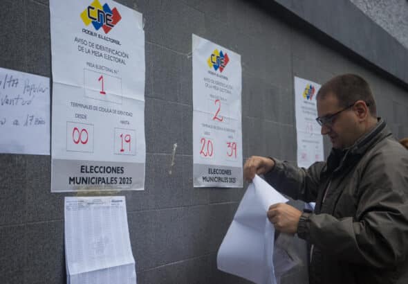 A man places the voting list at a polling station in Caracas this Sunday. Voting centers began opening their doors this Sunday in Venezuela. Photo: Boris Vergara/EFE.