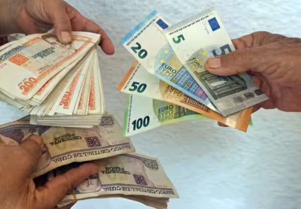 People hold Cuban peso, US dollar, and euro notes. Photo: EFE/Ernesto Mastrascusa.