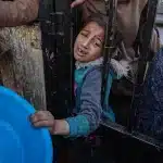 A child waits for food in line at a private food distribution center in Rafah, Gaza Strip, March 2025. Photo: Laoy Ayyoub.