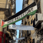 Palestinian flag flies in a street in Naples, Italy, with the words "Free Palestine" written on it. Photo: Zarefah Baroud/Palestine Chronicle.