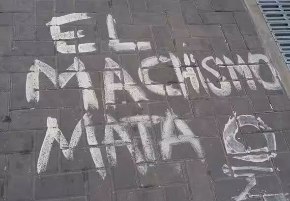 Painting on a sidewalk reading “Machismo Kills.” File photo.