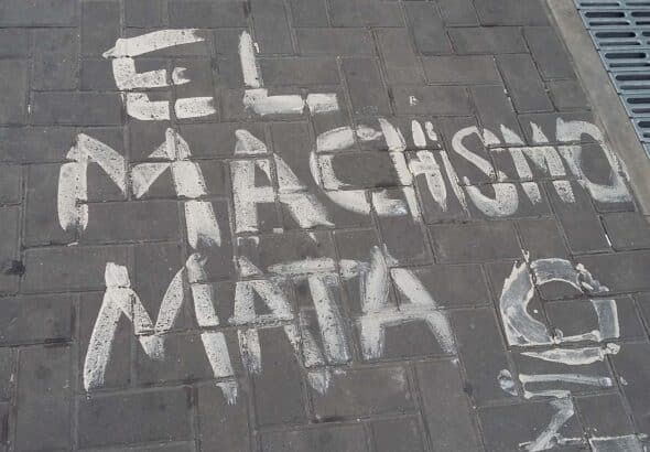 Painting on a sidewalk reading “Machismo Kills.” File photo.