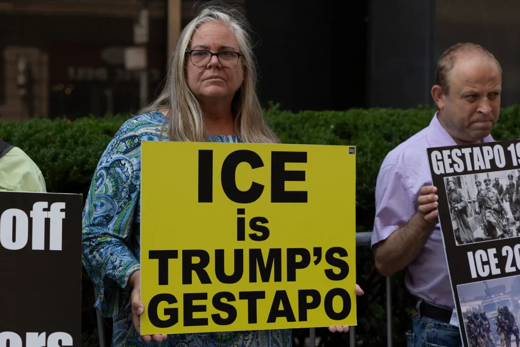 In front of the employee entrance at 26 Federal Plaza, in Manhattan's Civic Center, a member of Rise and Resist holds a sign that says "ICE is Trump's Gestapo" during a protest against the US Immigration and Customs Enforcement (ICE) and its agents for detaining immigrants. Photo: Gina M Randazzo/Zuma Press.