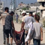 Palestinians carry the body of a person who was killed while seeking food at a distribution point run by the Gaza Humanitarian Foundation (GHF) on Salah al-Din Street in Nuseirat. Photo: AFP.