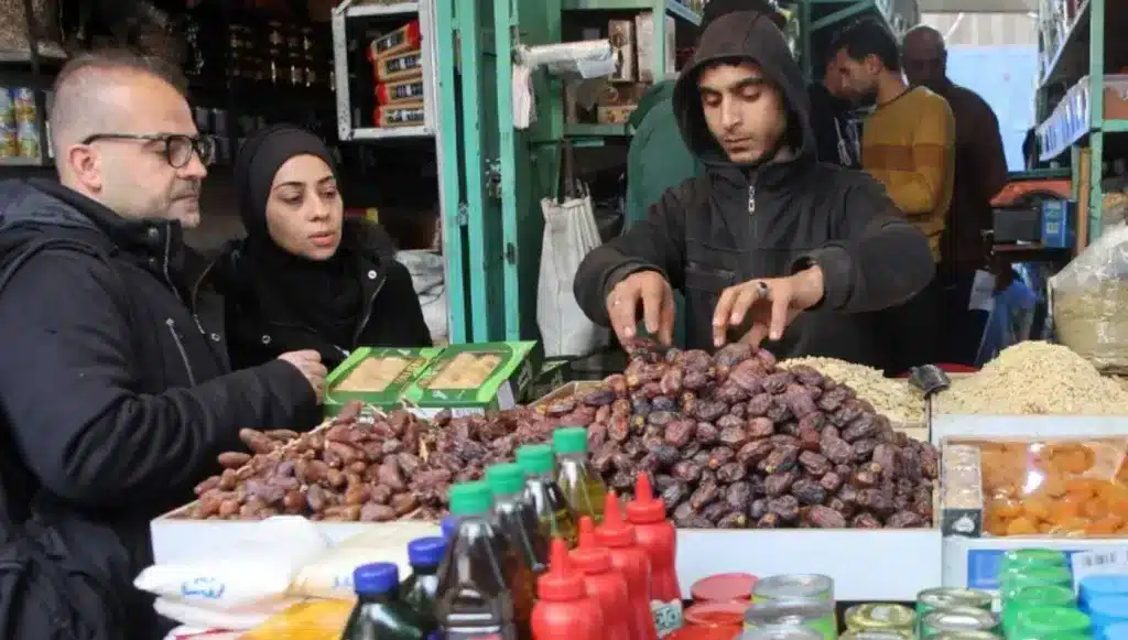 A vendor serves dates to a customer in Gaza City on 1 March 2025. Photo: Omar al-Qattaa/AFP.