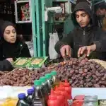 A vendor serves dates to a customer in Gaza City on 1 March 2025. Photo: Omar al-Qattaa/AFP.