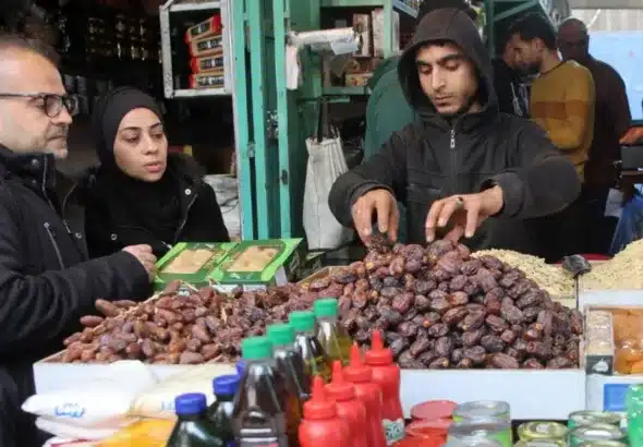 A vendor serves dates to a customer in Gaza City on 1 March 2025. Photo: Omar al-Qattaa/AFP.