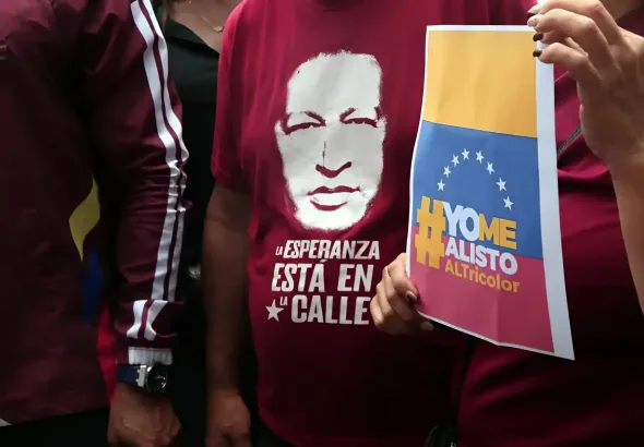 A person wears a t-shirt with the silhouette of President Hugo Chávez while another holds a paper sheet that reads "yo me enlisto" ("I am going to enlist"). Photo: Juan Carlos Hernández/contactophoto.