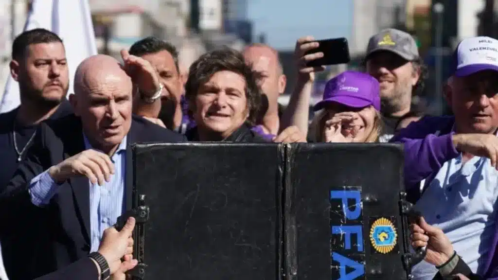 A suitcase is held in front of Argentine President Javier Milei as protesters throw bottles and rocks at the vehicle. Photo: Reddit.