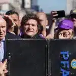 A suitcase is held in front of Argentine President Javier Milei as protesters throw bottles and rocks at the vehicle. Photo: Reddit.