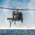 A US Sikorsky UH-60 Black Hawk helicopter conducting maritime operations with a special tactics airman descending into the water. Photo: US Air National Guard/file photo.