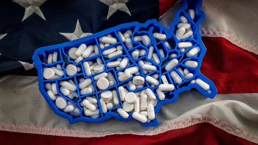 A plastic map of the United Statesâ states filled with pills, over a US flag. Photo: Victor Moussa/Shutterstock/file photo.