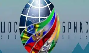 An image composition showing a logo of the globe, with BRICS member country flags superimposed on it, and the acronyms SCO and BRICS to each side. Photo: File photo.