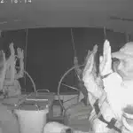 Hands in the air, a crew of a boat belonging to the Sumud Flotilla waits for Israeli settler colonial forces to board the ship and arrest them. Photo: Social video screenshot via Al Jazeera.