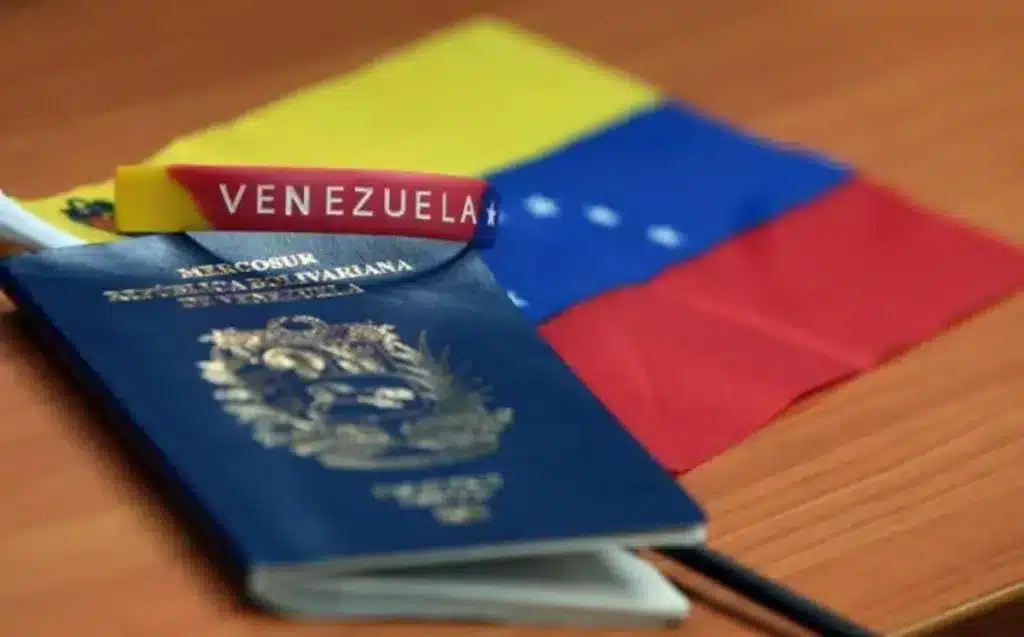 A Venezuelan passport, a bracelet with the inscription that reads "Venezuela," and a small flag of Venezuela over a desk. Photo: File photo.