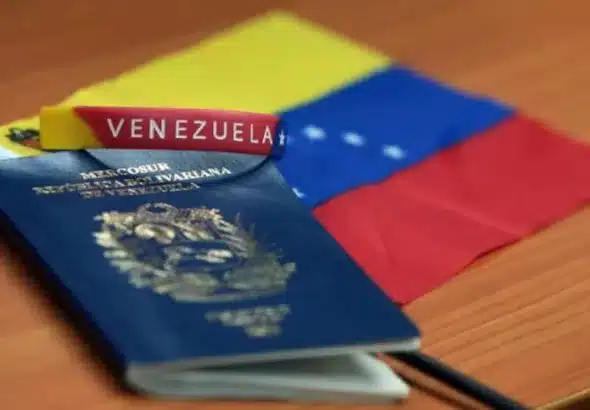 A Venezuelan passport, a bracelet with the inscription that reads "Venezuela," and a small flag of Venezuela over a desk. Photo: File photo.