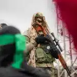A member of the Al-Qassam Brigades in combat fatigues standing before the ceremony for the handover of Israeli prisoners of war to the Red Cross in Nuseirat, Central Gaza Strip, Saturday, February 22, 2025. Photo: AP.