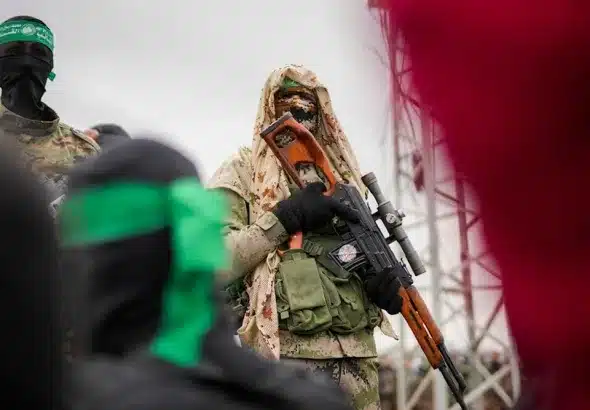 A member of the Al-Qassam Brigades in combat fatigues standing before the ceremony for the handover of Israeli prisoners of war to the Red Cross in Nuseirat, Central Gaza Strip, Saturday, February 22, 2025. Photo: AP.