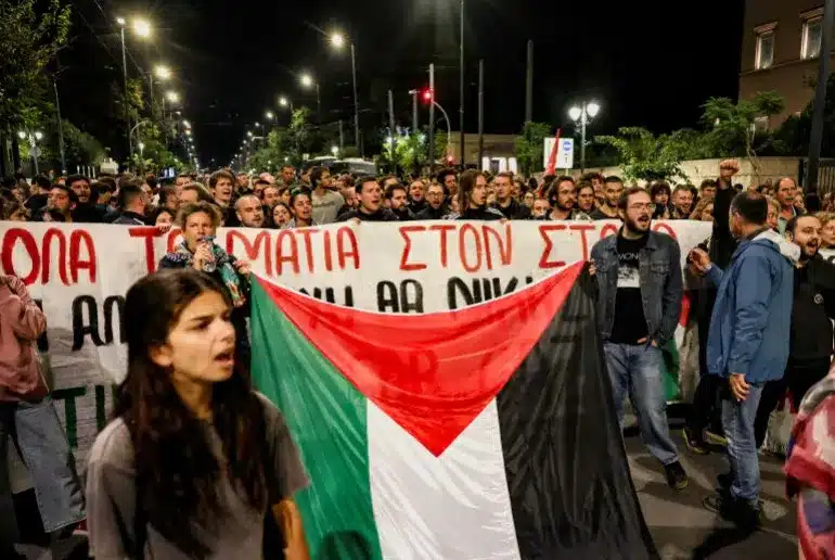Pro-Palestinian activists hold a banner and a Palestinian flag as they protest to condemn the interception of the vessels of the Global Sumud Flotilla. Photo: Louisa Gouliamaki/Reuters.