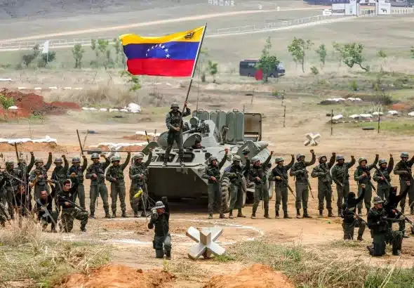 Venezuelan soldiers around a tank on which another soldier waves a Venezuelan flag during a military drill in Cojedes state. Photo: Presidential Press/file photo.