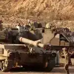 An Israeli trooper stands in front of a self-propelled howitzer stationed along the Gaza Strip’s border with the occupied Palestinian territories, September 30, 2025. Photo: AFP.