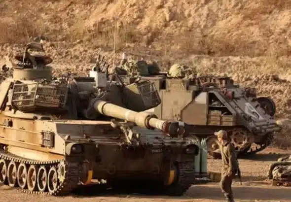 An Israeli trooper stands in front of a self-propelled howitzer stationed along the Gaza Strip’s border with the occupied Palestinian territories, September 30, 2025. Photo: AFP.