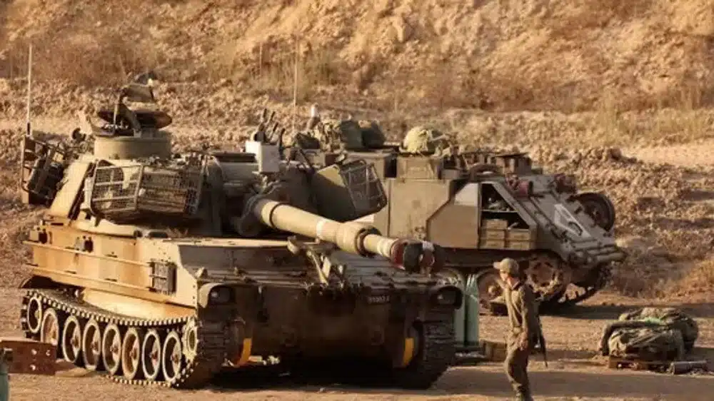 An Israeli trooper stands in front of a self-propelled howitzer stationed along the Gaza Strip’s border with the occupied Palestinian territories, September 30, 2025. Photo: AFP.