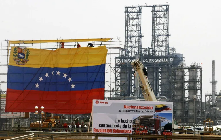 Oil workers hang a Venezuelan flag at the Jose Complex during celebrations in Barcelona, Venezuela, May 1, 2007, as the state-run oil company PDVSA takes control of oil fields in the Orinoco Belt. Photo: Jorge Silva/Reuters/file photo.