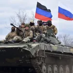 Soldiers on an armored personnel carrier (APC) carrying the flag of the Russian Federation and the flag of the Donetsk People's Republic. Photo: New Eastern Outlook.