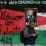 The image shows a passerby in front of a mural that reads "Mexico with Palestine." Photo: Al Akhbar/file photo.