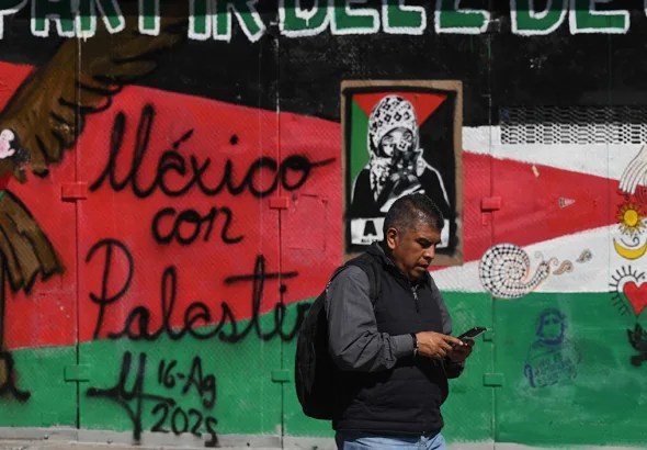 The image shows a passerby in front of a mural that reads "Mexico with Palestine." Photo: Al Akhbar/file photo.