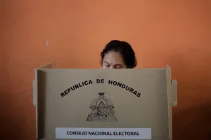 A person participates in an election in Honduras, using a voting booth provided by the National Electoral Council. The booth displays the coat of arms and name of the Republic of Honduras. Photo: Jorge Cabrera/Reuters/file photo.