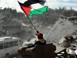 A Palestinian child raises the flag over the ruins of his home — a reminder that no imposed plan can extinguish the struggle for self-determination. Photo: Struggle La Lucha.