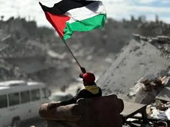 A Palestinian child raises the flag over the ruins of his home â a reminder that no imposed plan can extinguish the struggle for self-determination. Photo: Struggle La Lucha.
