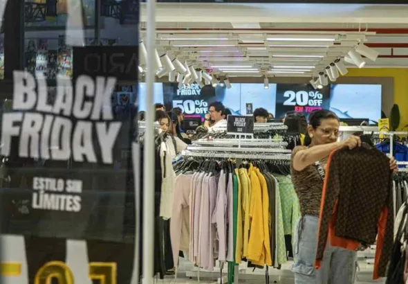 Photograph of a woman holding clothing inside a store during Black Friday in Maracaibo, Venezuela. Photo: EFE/Henry Chirinos.