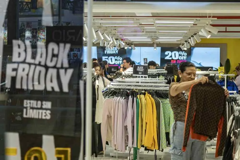 Photograph of a woman holding clothing inside a store during Black Friday in Maracaibo, Venezuela. Photo: EFE/Henry Chirinos.