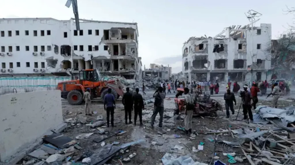 People standing near the wreckage of a recent Shabab-claimed suicide car bomb attack on a hotel in Mogadishu, Somalia. Photo: Feisal Omar/Reuters.