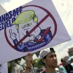 A protester holds a "Hands Off Venezuela" poster at an anti-imperialist protest in Caracas, Venezuela. Photo: AP/Ariana Cubillos.