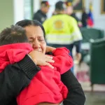 An emotionally shaken Venezuelan woman holds a child arriving in a repatriation flight from the US empire on Wednesday, November 26, 2025. Photo: IG/@vueltalapatria.