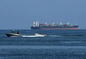 A Venezuelan Navy coast guard boat helps a small fishing boat near a large cargo ship on September 11, 2025. Photo: Juan Carlos Hernandez/Reuters/file photo.