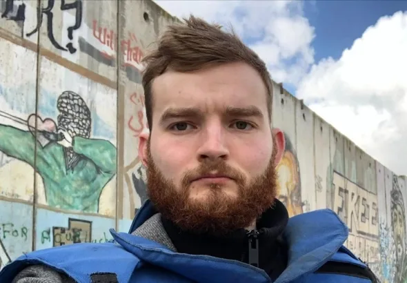 Robert Inlakesh in front of the separation wall at the Qalandia checkpoint, occupied West Bank, in February 2020. Photo: Robert Inlakesh/file photo.