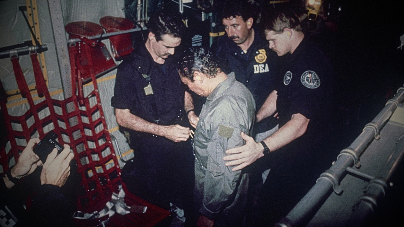 Manuel Antonio Noriega watches as U.S. Drug Enforcement Agents place chains around his waist aboard a C-130 transport plane on Jan. 4, 1990. Noriega surrendered to U.S. authorities in Panama City and was flown to Miami, Florida, where he faced drug trafficking charges. Photo: AP.