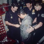 Manuel Antonio Noriega watches as U.S. Drug Enforcement Agents place chains around his waist aboard a C-130 transport plane on Jan. 4, 1990. Noriega surrendered to U.S. authorities in Panama City and was flown to Miami, Florida, where he faced drug trafficking charges. Photo: AP.