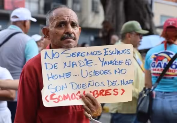 A man holds a sign saying: “We will not be anyone’s slaves… Yankee go home… You are not the owners of the world… We are free.” Photo: Ciudad Valencia.