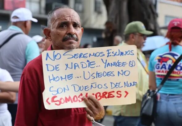 A man holds a sign saying: “We will not be anyone’s slaves… Yankee go home… You are not the owners of the world… We are free.” Photo: Ciudad Valencia.