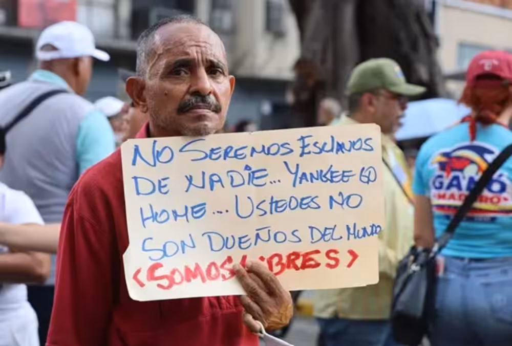 A man holds a sign saying: “We will not be anyone’s slaves… Yankee go home… You are not the owners of the world… We are free.” Photo: Ciudad Valencia.
