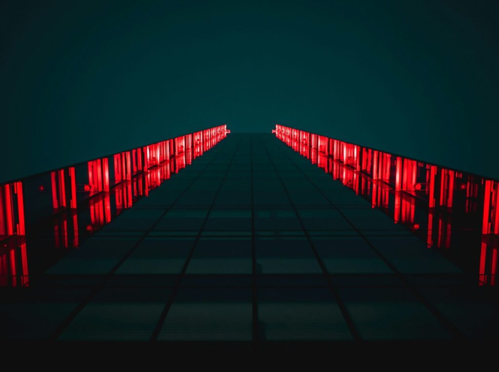 low-angle photograph of a modern building facade at night, illuminated by bright red vertical lights. Photo: Tanner Boriack.