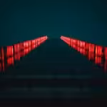 low-angle photograph of a modern building facade at night, illuminated by bright red vertical lights. Photo: Tanner Boriack.