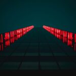 low-angle photograph of a modern building facade at night, illuminated by bright red vertical lights. Photo: Tanner Boriack.