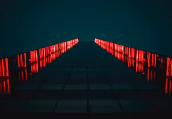 low-angle photograph of a modern building facade at night, illuminated by bright red vertical lights. Photo: Tanner Boriack.
